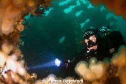 Diver peering through a hole on the Tapti wreck, Isle of ... by Marcus Blatchford 